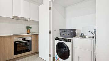 A compact kitchen with a Bosch oven, a front-loading washing machine, and a sink.