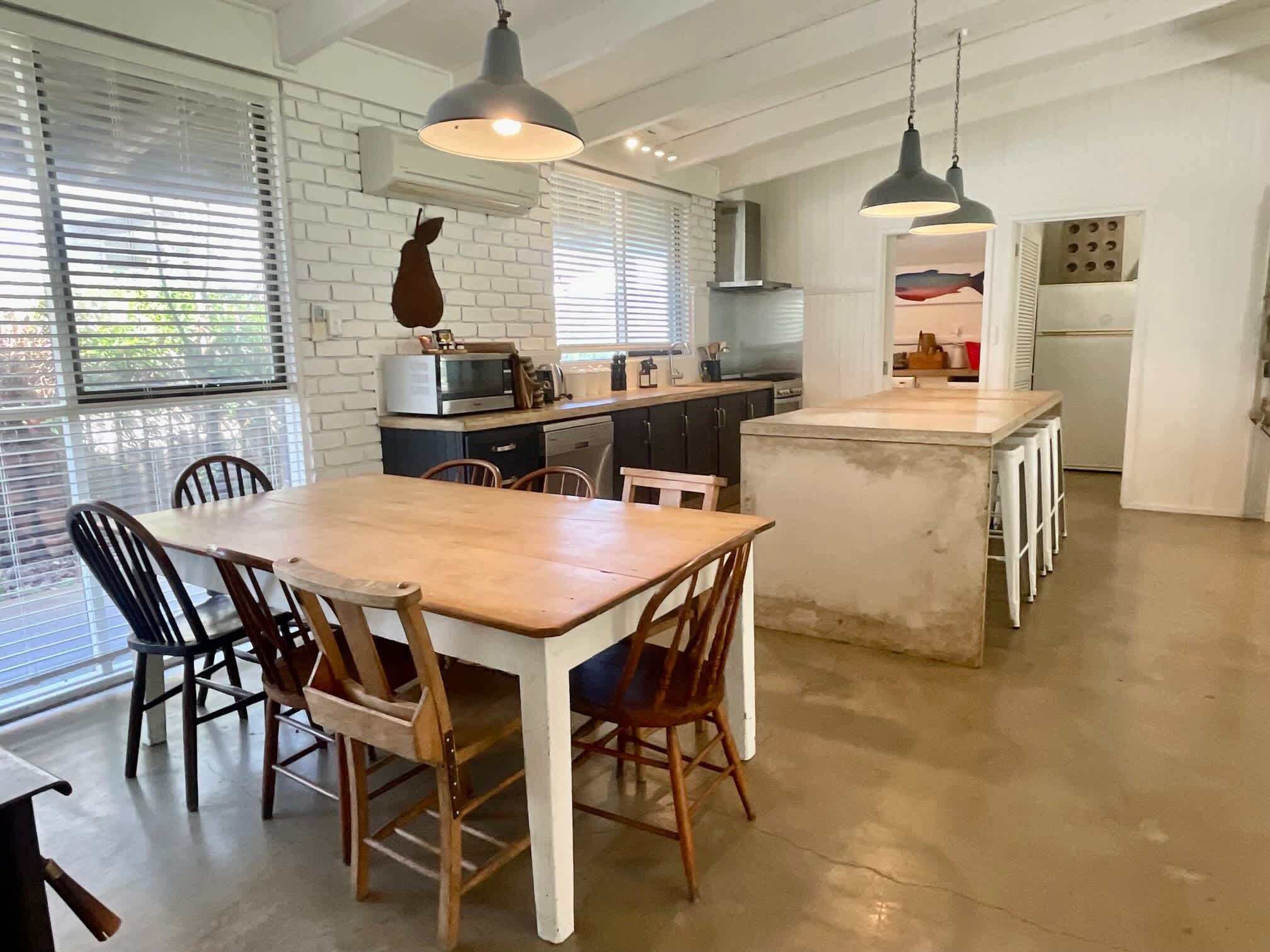 A kitchen with a dining area, white brick walls, and pendant lighting.