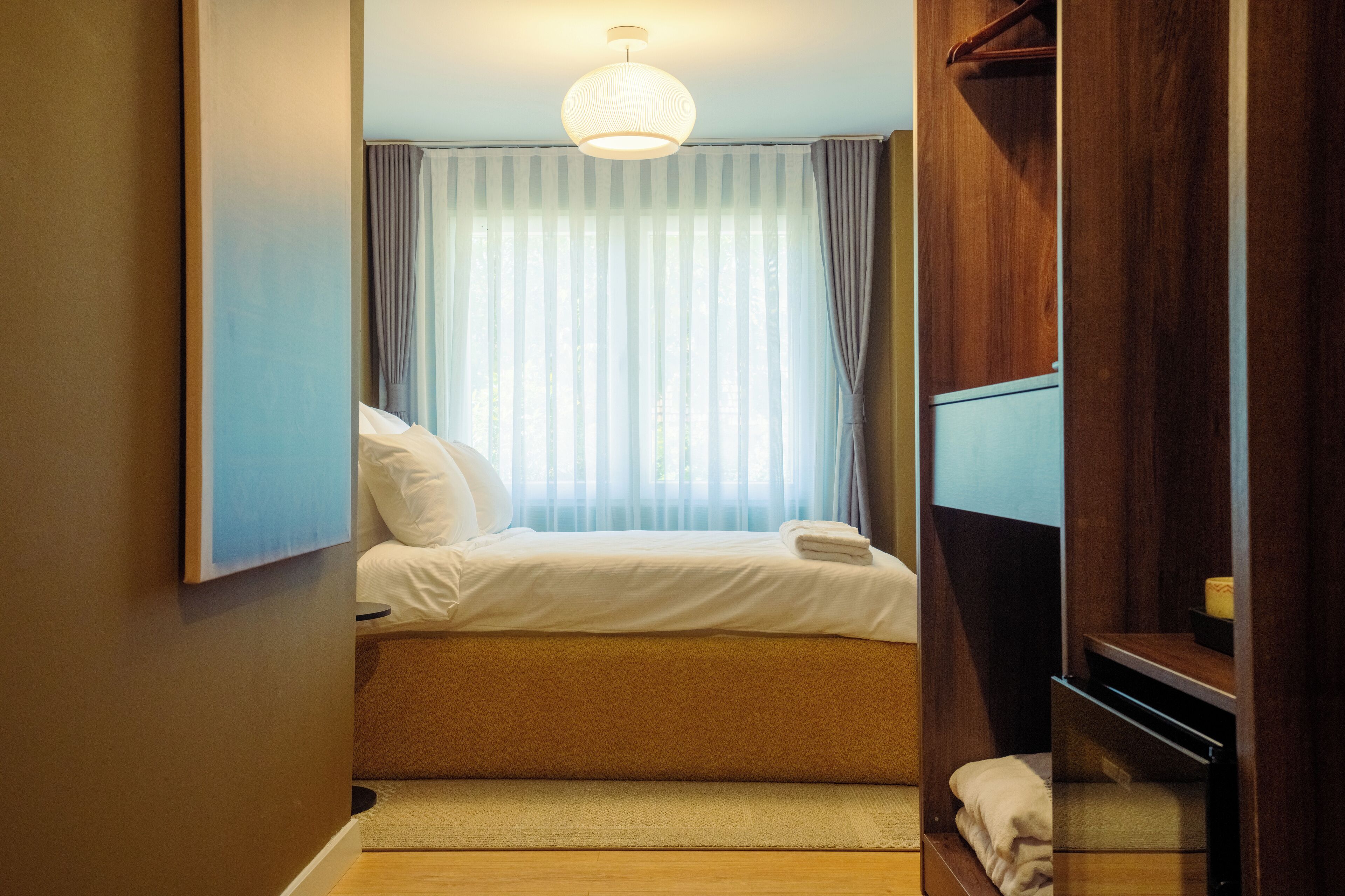 A hotel room with a bed, a television, and a window with curtains.
