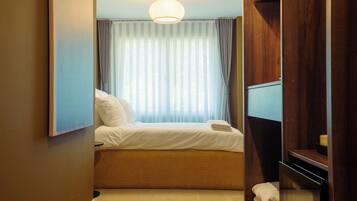 A hotel room with a bed, a television, and a window with curtains.
