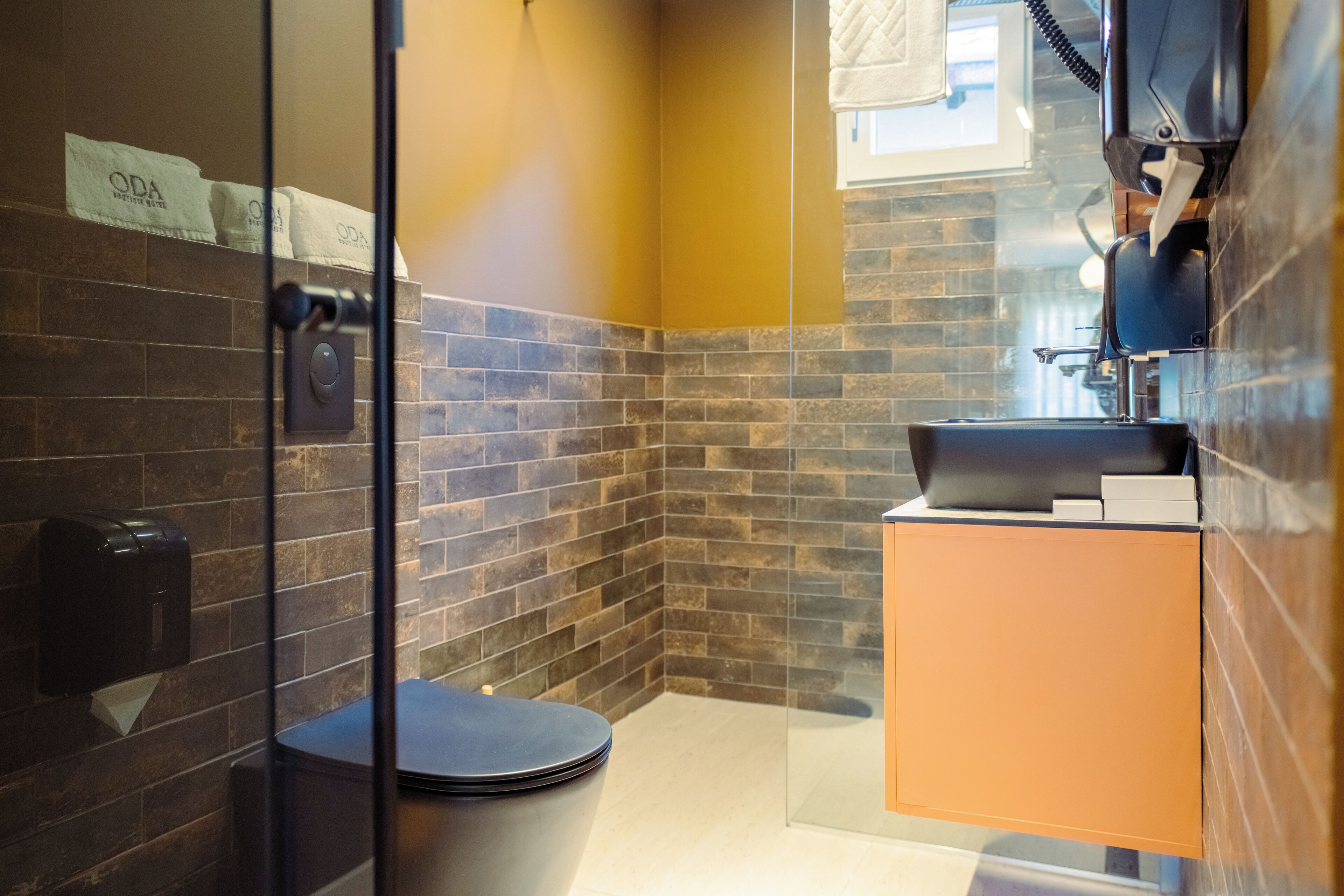 Une salle de bain moderne avec une douche à parois de verre, des toilettes noires et un meuble-lavabo en bois.