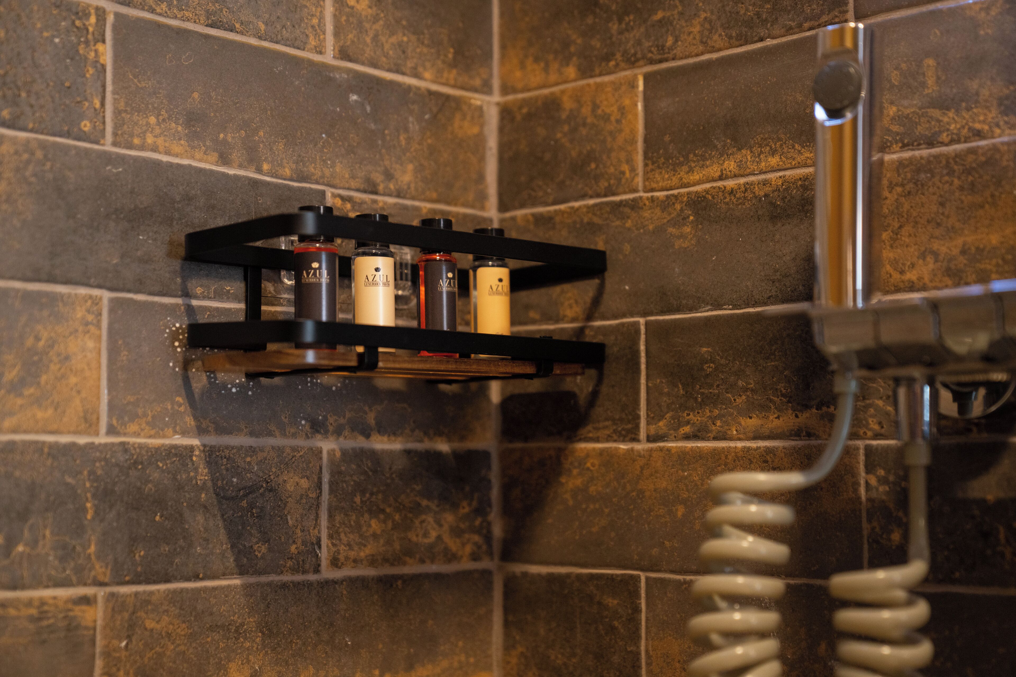 Un baño con cabezal de ducha, toallero y estante con artículos de tocador.