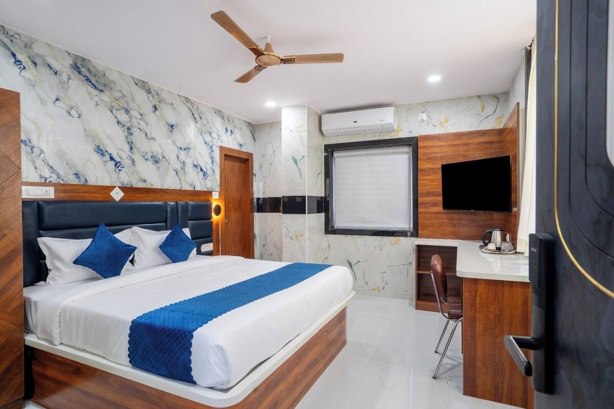 Habitación de hotel moderna con una cama grande, un escritorio, un ventilador de techo, un aire acondicionado y un televisor.