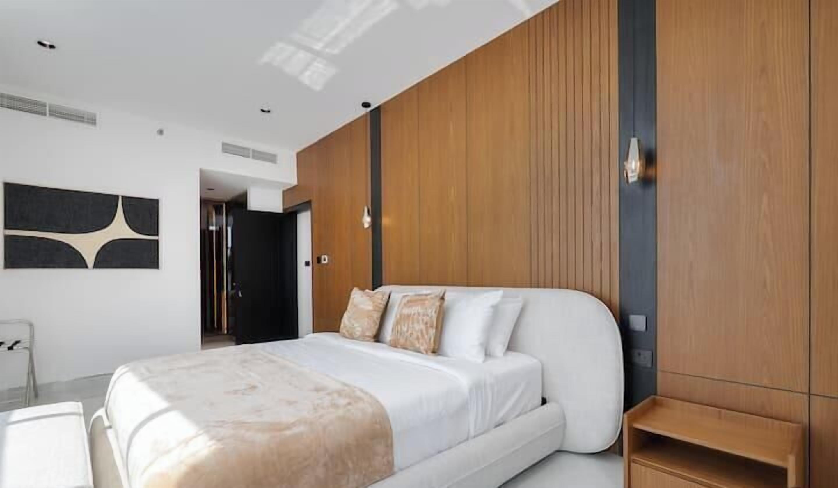 Un dormitorio moderno con una cama grande, un armario de madera y una obra de arte colgada en la pared.