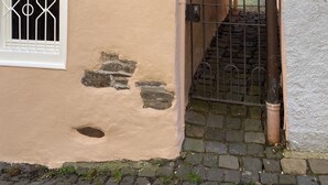 Ein traditionelles Fachwerkhäuschen mit einer Steintreppe, die zu einem verschlossenen Eingang führt.