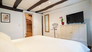 Ein Schlafzimmer mit einem Bett, einem Fernseher, einem Kleiderschrank und einer Tür zu einer Treppe.