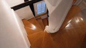 Eine Treppe mit braunen Fliesen, ein Fenster mit Aussicht und weiße Vorhänge.
