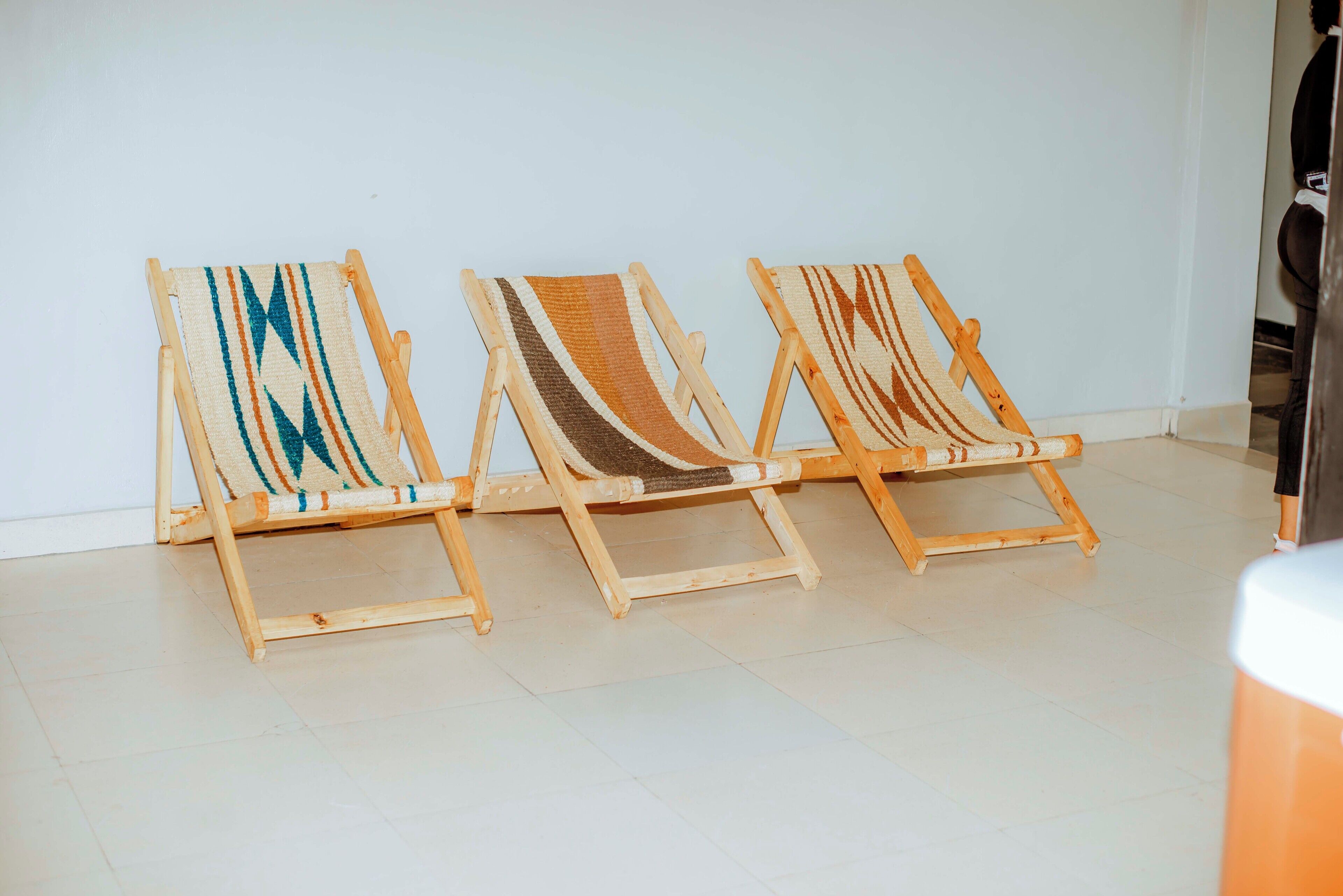 Tres sillones de madera con asientos cubiertos de tejido frente a una pared lisa.