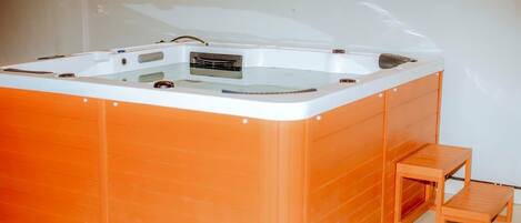 Un jacuzzi con un banco de madera y una pequeña mesa.