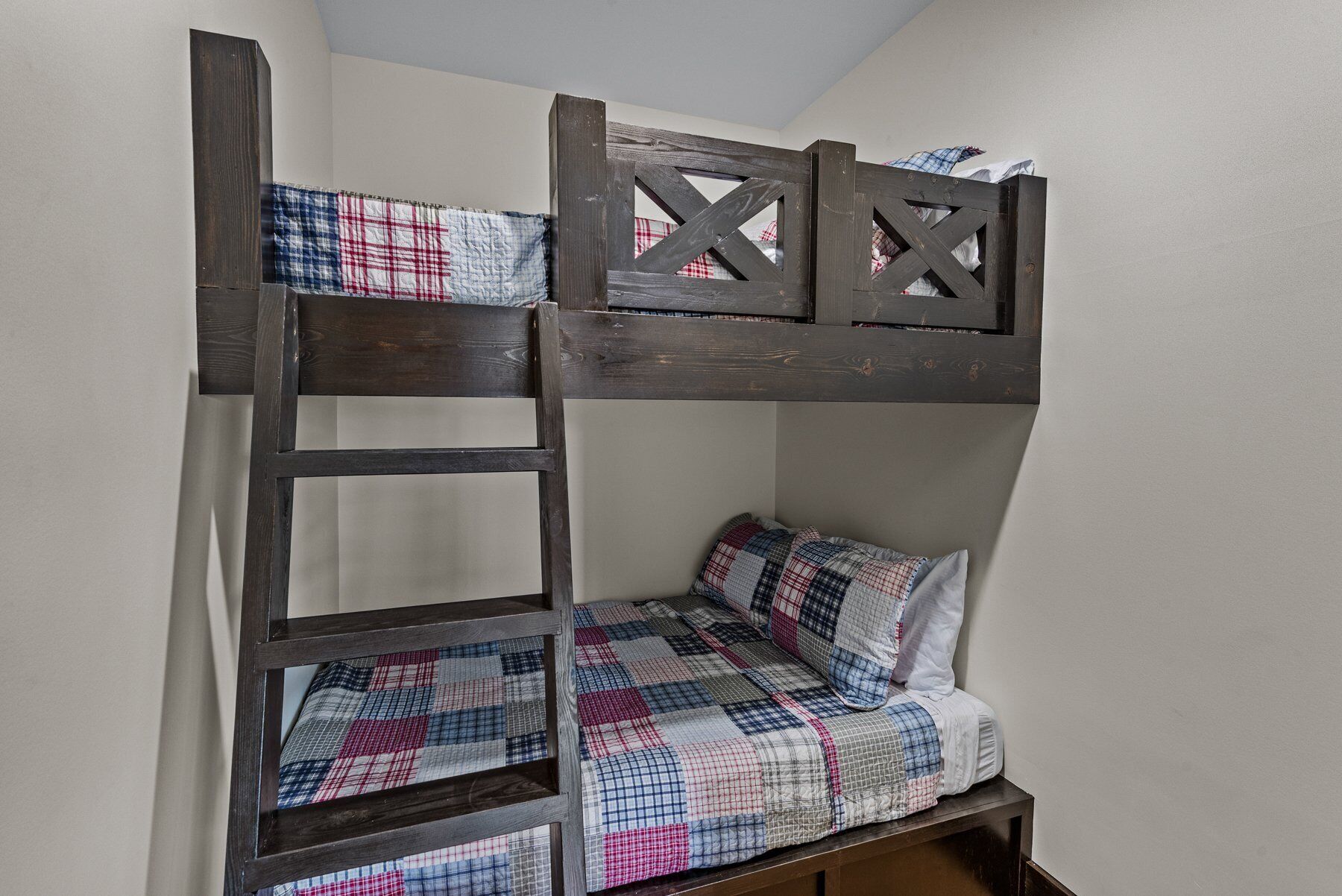 Una cama litera con escalera, un colchón acolchado y un cabecero de madera.
