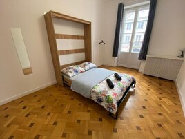Une chambre à coucher avec un cadre de lit en bois, une couvre-lit à motifs floraux et une fenêtre avec des rideaux.