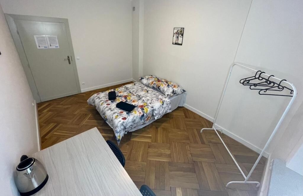 Une petite pièce comprenant un lit, un bureau et un porte-manteau.