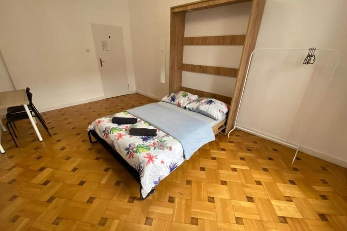 Ein Schlafzimmer mit einem Bettgestell aus Holz, einer blauen Bettdecke und einem Blumenkissen.