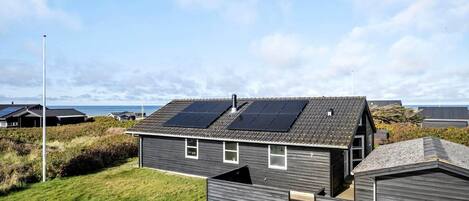 Ein Wohngebäude mit Schrägdach, Solaranlage und Rasengarten.