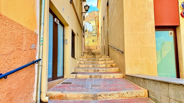 A narrow alleyway with a stone staircase leading up to a building.