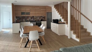 A modern kitchen with wooden cabinetry, a central island, and a dining area with a wooden table and white chairs.