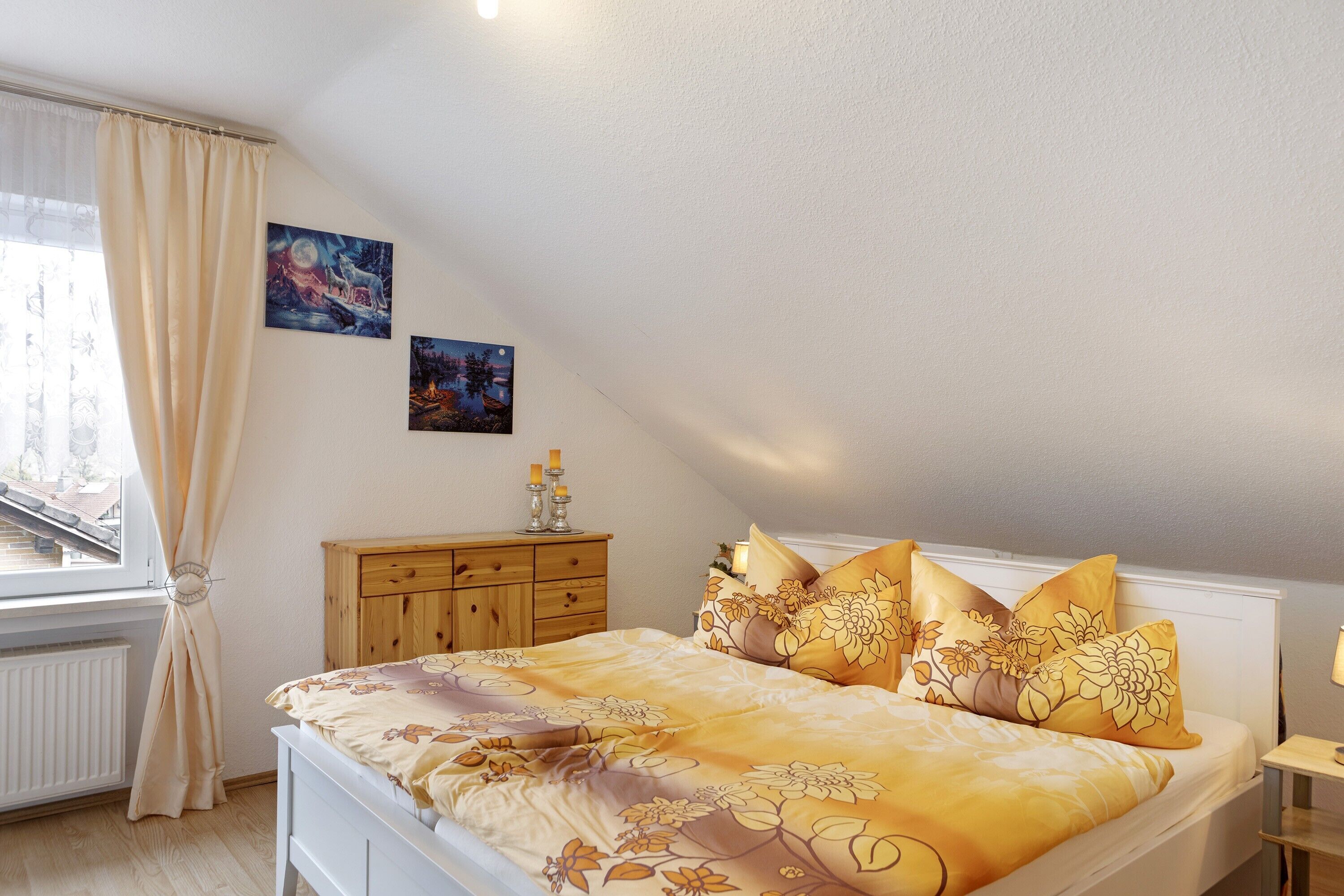 Een slaapkamer met een bed, nachtkastje, kledingkast en een raam met gordijnen.