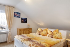 A bedroom with a bed, a nightstand, a dresser, and a window with curtains. - Apartment 'Rosenrot' with Wi-Fi (Naumburg)