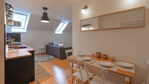 A modern kitchen with a dining area, a large mirror, and a skylight.