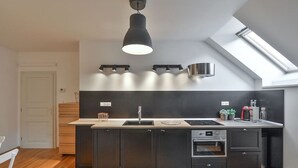 A modern kitchen with a skylight, dark cabinetry, a built-in oven, and a light fixture above the counter.
