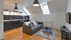 A modern apartment with a kitchen, a gray sofa, a coffee table, and a TV.