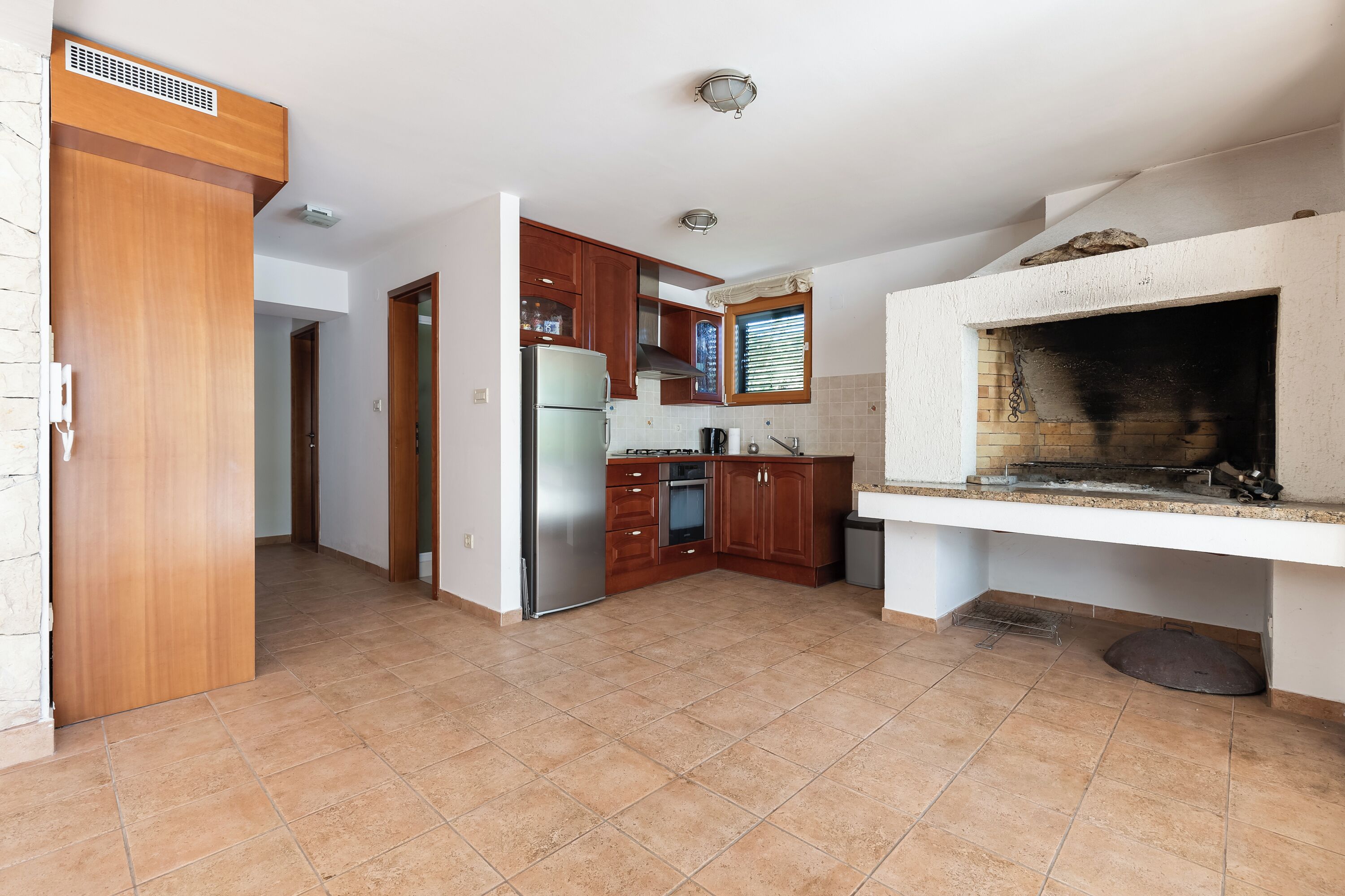 A kitchen with wooden cabinets, a built-in oven, and a stone fireplace.