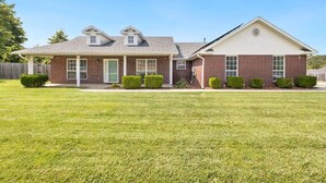 A two-story house with a front porch, a garage, and a well-maintained lawn. - Quiet Razorback Escape - Easy Drive to Downtown & Stadium (Fayetteville)