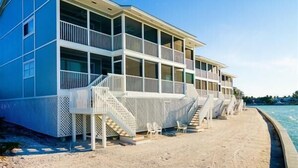 Een strandhotel met meerdere balkons, een zandstrand en een zwembad.