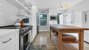 Een moderne keuken met witte kasten, een houten tafel en een inbouwoven.