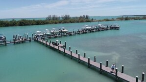 Een jachthaven met boten afgemeerd aan een houten steiger die zich uitstrekt in turquoise water.