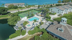 An aerial view of a resort with a large pool, tennis courts, and a view of the ocean. - Boca Grande North - 08: 2BR condo with water views, pool, and hot tub in Boca Grande, FL. (Boca Grande)