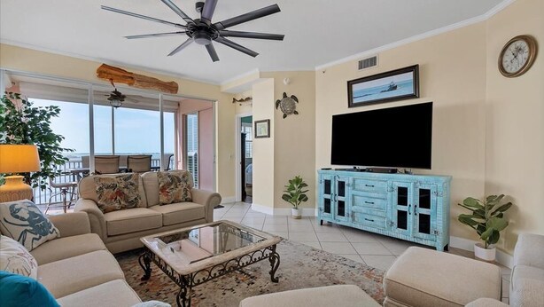 A living room with a beige sofa, a glass coffee table, a blue cabinet, and a ceiling fan. - Boca Vista Harbor - 401D: Spacious 3BR condo in Placida, FL, perfect for 6 guests. (Placida)