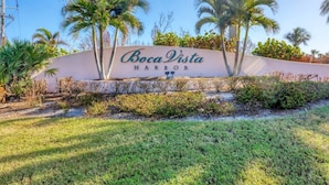 A sign for Boca Vista Harbor with palm trees and a grassy area in the foreground. - Boca Vista Harbor - 401D: Spacious 3BR condo in Placida, FL, perfect for 6 guests. (Placida)