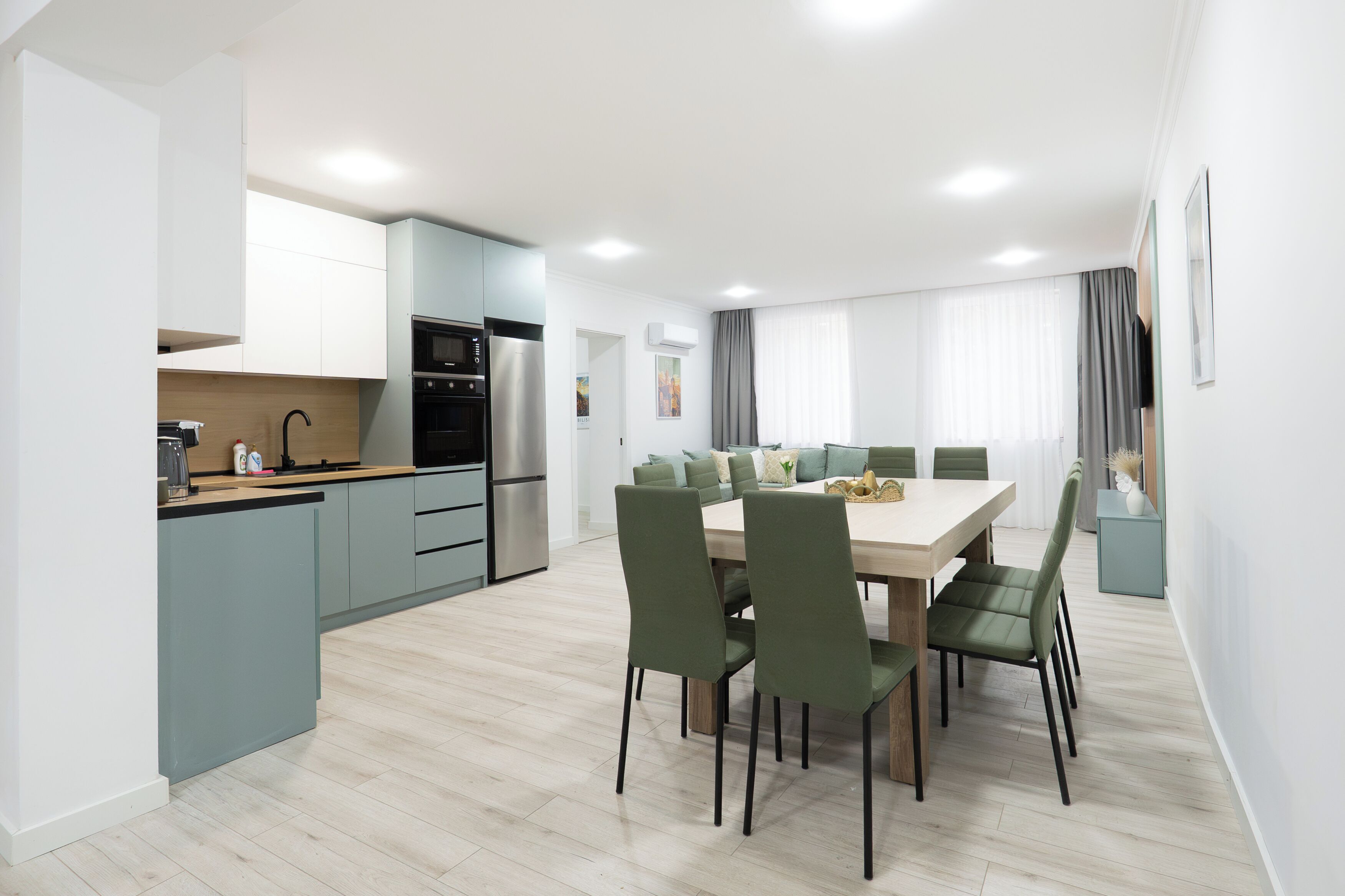 A modern kitchen with built-in appliances, a dining area with a large table and chairs, and a view of the living room.