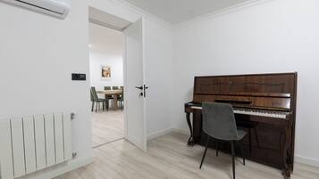A room with a piano, a radiator, and a door leading to another room.