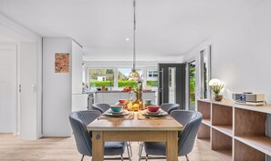Un comedor moderno con una mesa de madera, sillas grises y una lámpara colgante.