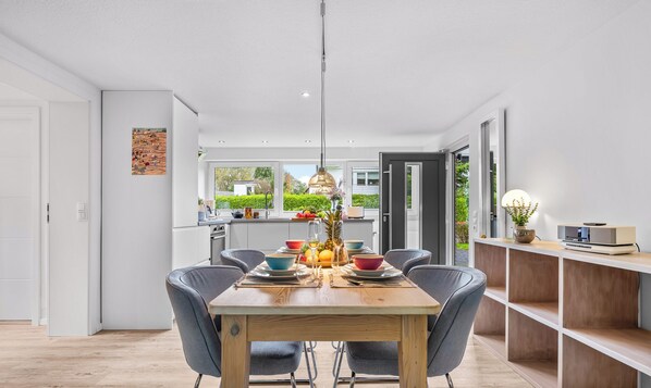 Un espace repas moderne avec une table en bois, des chaises grises et une suspension.