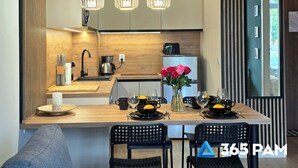 A modern kitchen with wooden cabinetry, a central island with seating, and pendant lighting. - Apartament Ku Morzu 27 - 365PAM (Sianożęty)