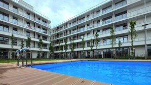 A modern building with a swimming pool, multiple balconies, and a wooden deck. - Apartament Ku Morzu 27 - 365PAM (Sianożęty)
