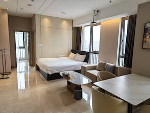 A modern hotel room with a bed, a sofa, a dining table, and a trash bin. - Chengdu Anjia High Altitude Hotel (Chengdu)