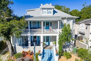A two-story house with a balcony, a front porch, and a small outdoor seating area.