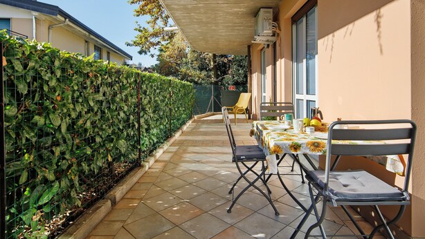 An outdoor patio with a table and chairs, a covered area, and a hedge. - Casa Vacanze “Martina” with Private Terrace near Lake Como (San Fermo della Battaglia)