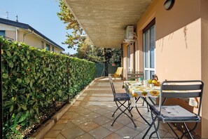 Une terrasse extérieure avec une table et des chaises, un espace abrité et une haie.