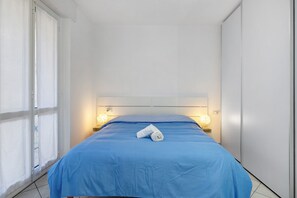 Une chambre d’hôtel avec un lit, deux lampes de chevet, une fenêtre avec des rideaux et une serviette sur le lit.