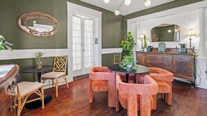 A dining area with a round table, cushioned chairs, a chandelier, and a wooden cabinet with a mirror. - Pullman Room | Team Joseph Ellen (St. Augustine)