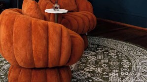A dark room with a large mirror, a white bust, and two orange poufs with a small table and incense sticks. - Flower Room | Team Joseph Ellen (St. Augustine)