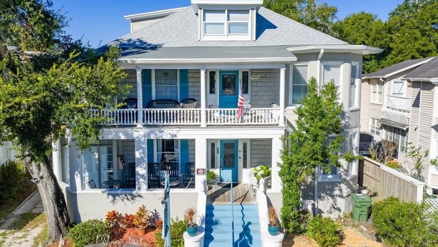 A two-story house with a balcony, a front porch, and a small outdoor seating area. - Flower Room | Team Joseph Ellen (St. Augustine)