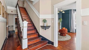 A staircase with wooden steps and white railings, a dark blue wall, and a round rug with a plant. - Crystal Room | Team Joseph Ellen (St. Augustine)