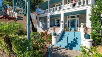 A two-story building with a porch, steps leading to the entrance, and a sign indicating it is a bed and breakfast.