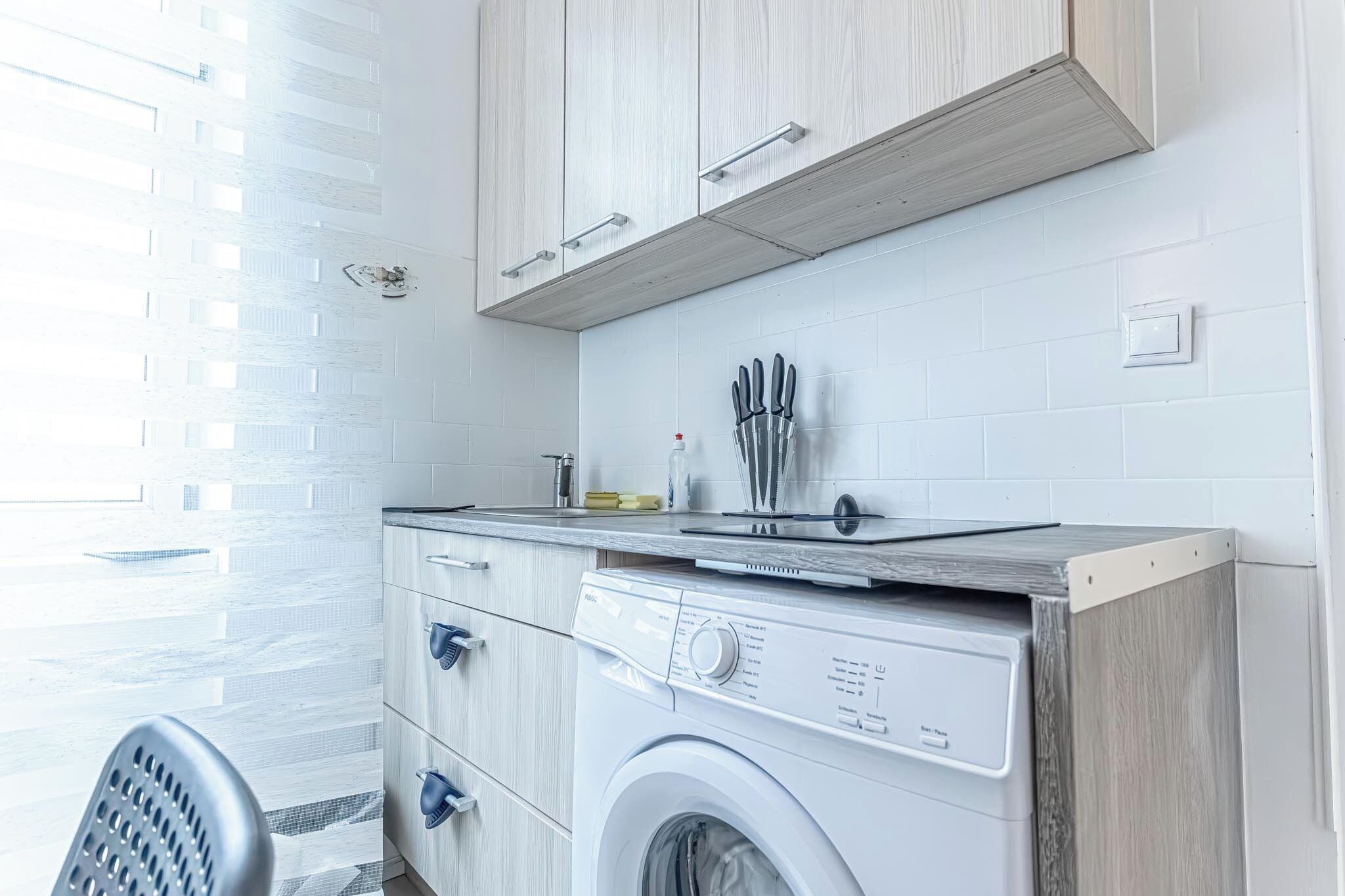 A compact laundry room with a washing machine, a dryer, and a countertop with a knife set.